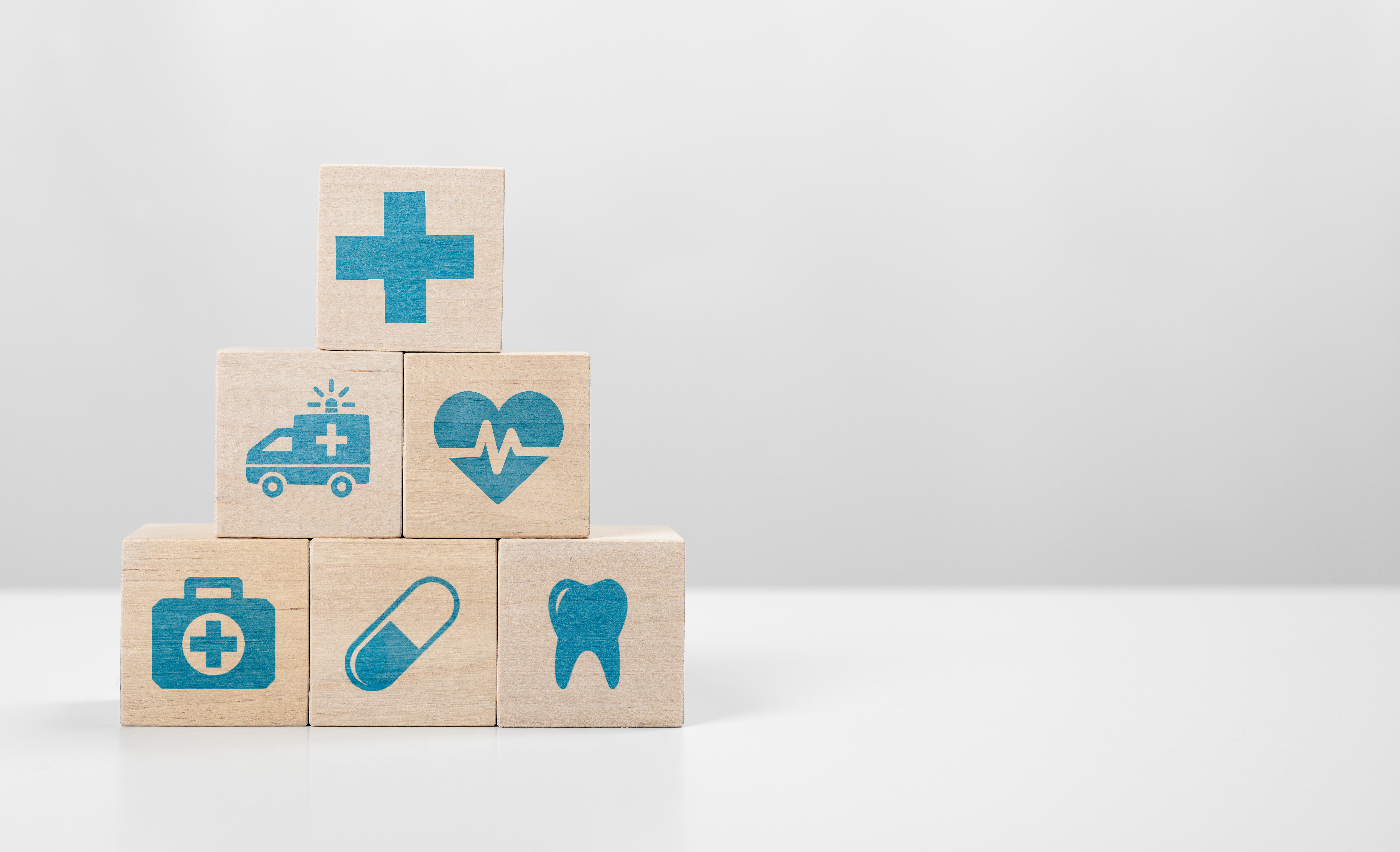 A white background with wood building blocks with icons of health and care on them