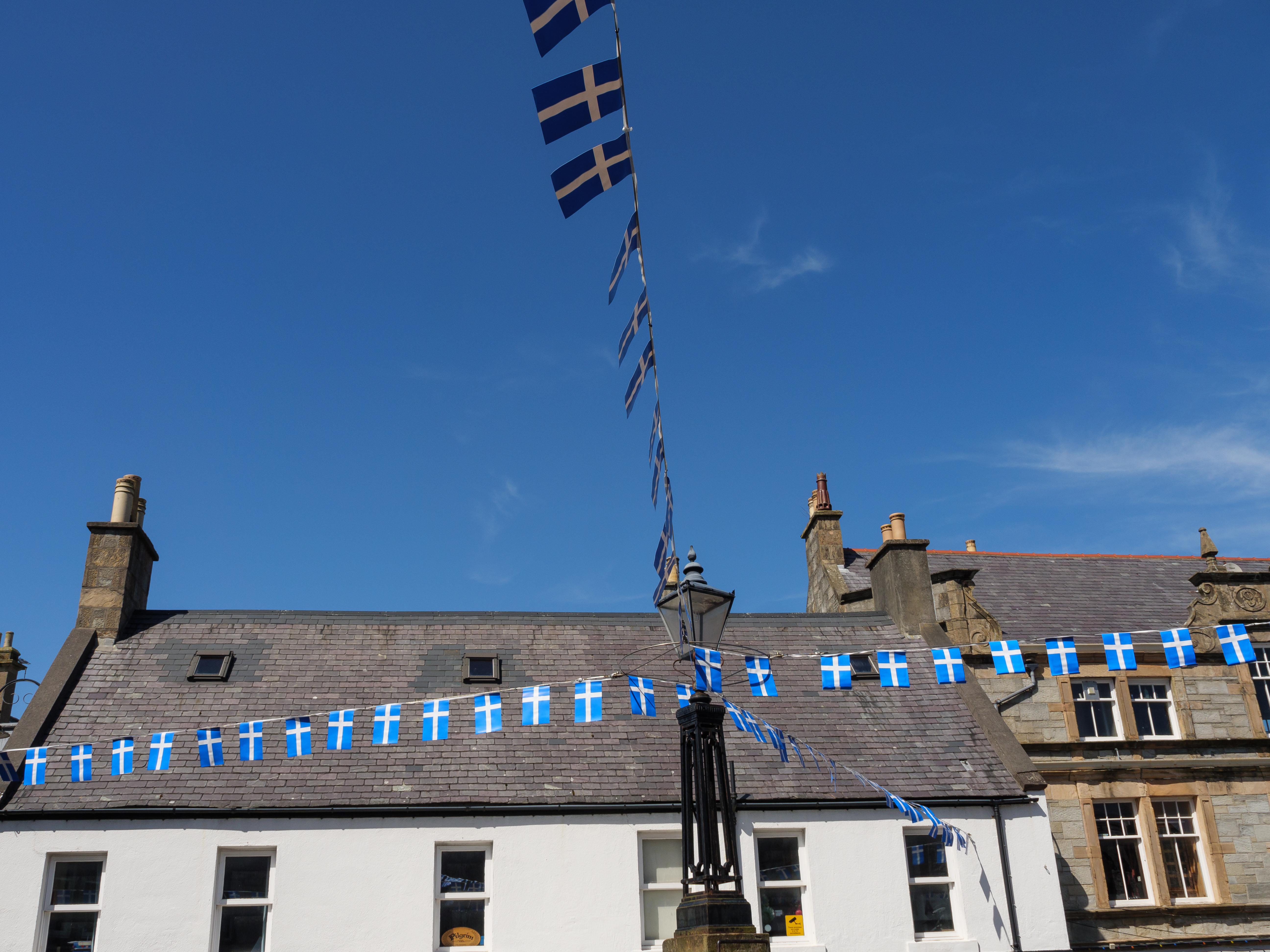 Bunting displaying Shetland flags (white nordic cross on a blue background), on the buildings in Lerwick.
