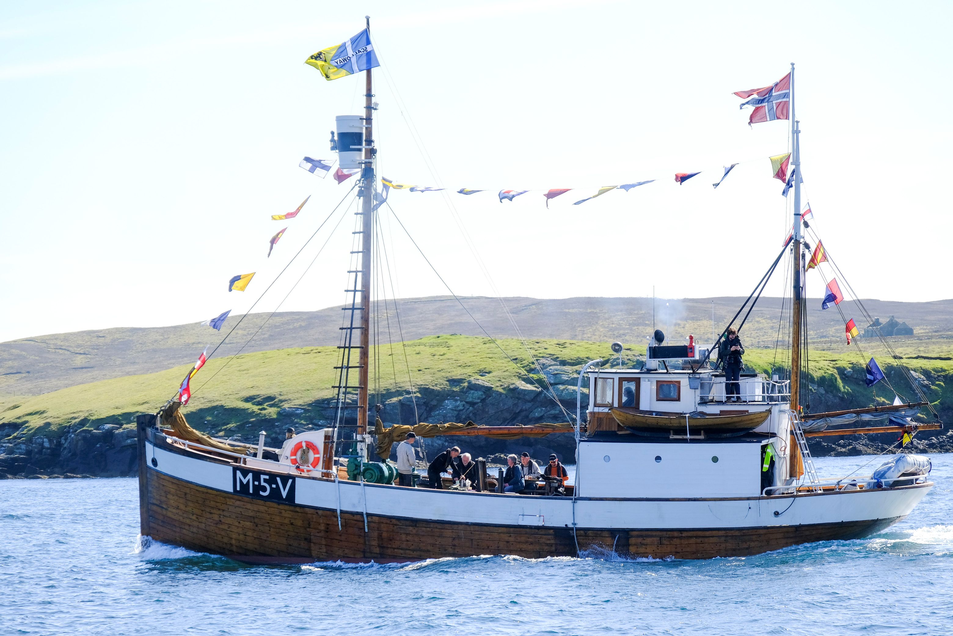 A small convoy boat at sea, with flags flying