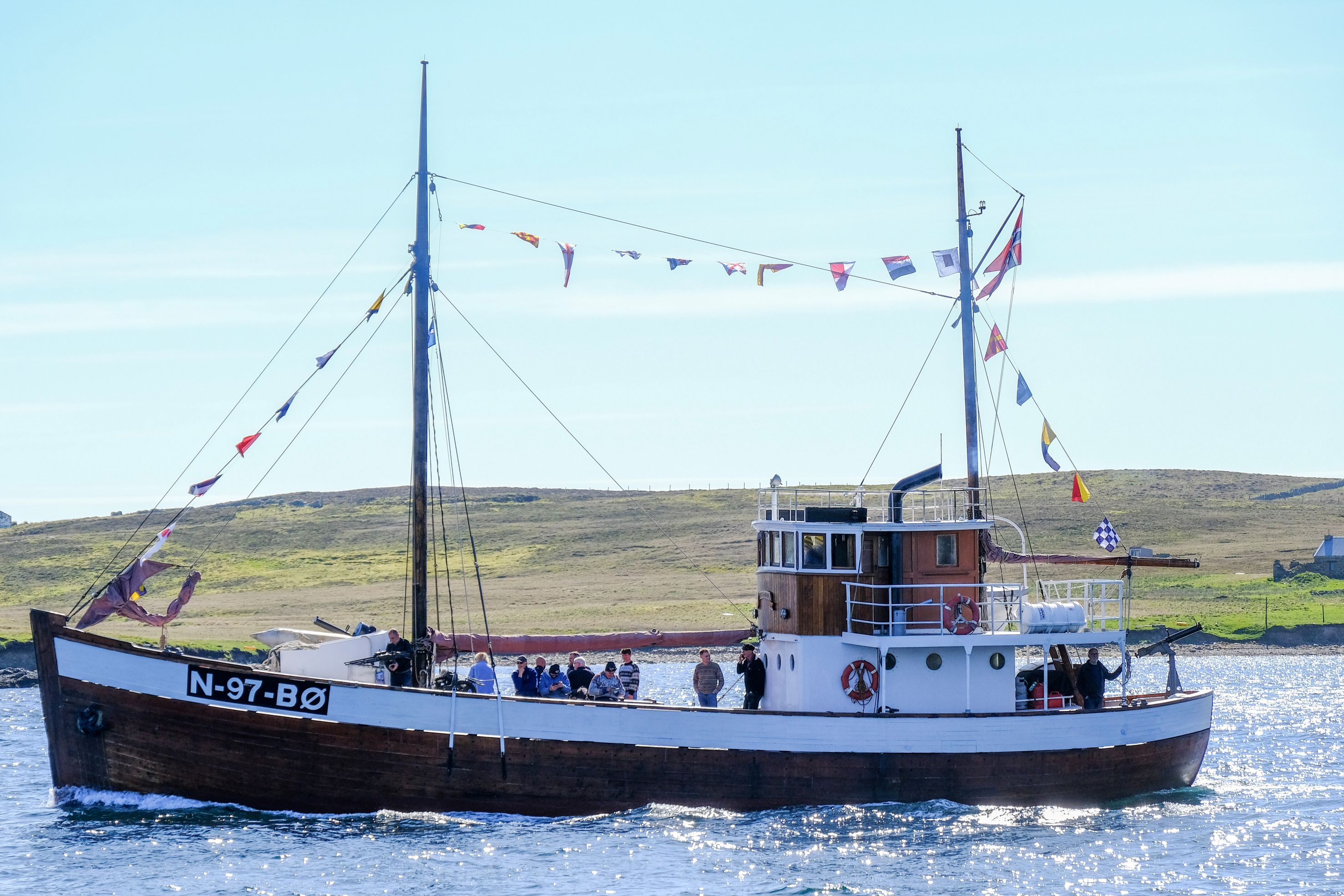 A third small convoy boat at sea with crew looking on from the deck