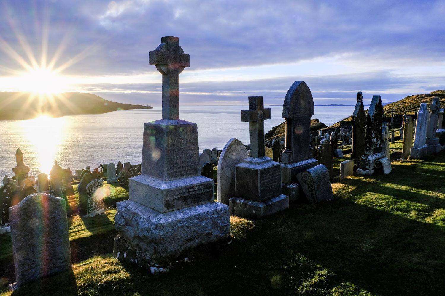Knab cemetery - view of the morning sun over Bressay with silhouettes of headstones.  Credit: SIC