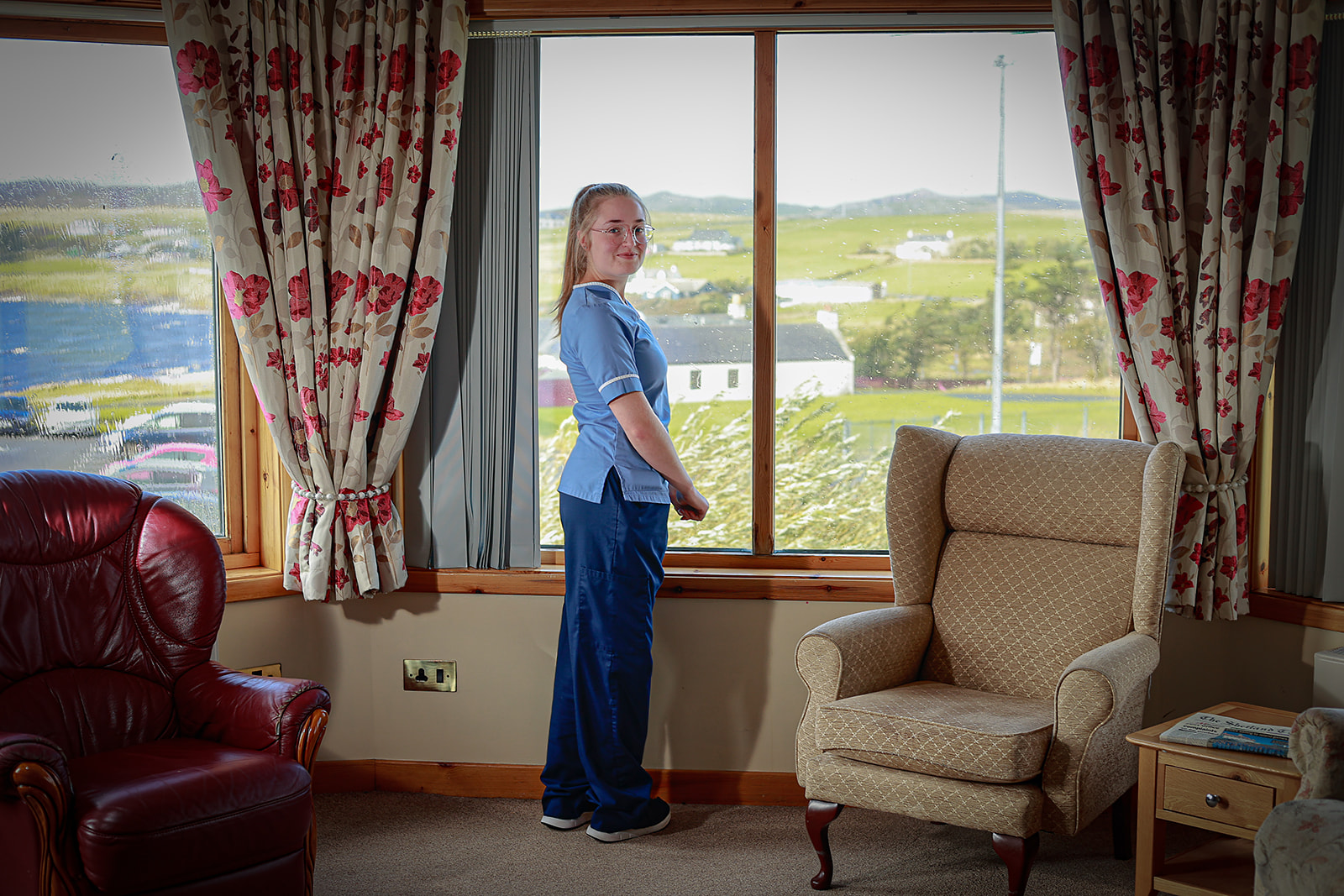 A care worker stands in the window of a care facility.