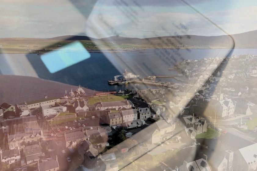 A composite image of a storage heater superimposed on an aerial view of Lerwick harbour.