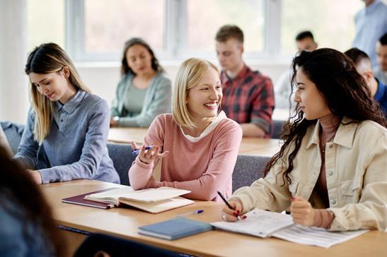 A group of students in a classroom. Some have books open.